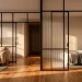 Modern studio apartment featuring a chic black metal and fluted glass room divider with soft natural sunlight.