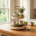 Beautifully styled white wooden tiered tray for St. Patrick's Day featuring shamrock cookies, gold foil candies, and rustic moss on a modern kitchen island.