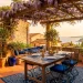 Sun-drenched Mediterranean backyard patio with terracotta tiles, rustic pergola, and outdoor dining table