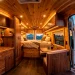 Luxurious custom camper van interior showcasing artisan woodwork with warm lighting and open rear doors facing a sunset