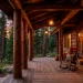 Rustic wood cabin front porch with log columns and cozy rocking chairs at sunset.