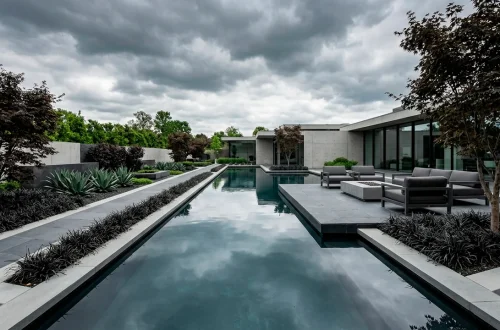 Wide landscape view of a modern patio featuring a minimalist dark slate pond with sharp geometric lines.