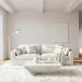 Sleek all-white minimalist living room featuring a comfortable linen sofa and modern marble coffee table bathed in natural sunlight.