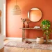 Vibrant boho entryway featuring a warm terracotta accent wall, vintage runner rug, and a rattan pendant light.