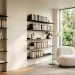 Modern minimalist home library featuring sleek black floating shelves, a white boucle chair, and warm natural lighting.