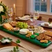 Elegant emerald green and wood appetizer tray filled with cheese and fruit on a festive St. Patrick's Day table setting.