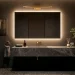 Modern powder room interior with glowing backlit mirror and warm brass lighting elements.