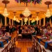 Luxurious maximalist wedding reception hall showcasing vibrant jewel-toned floral arrangements and emerald drapes.