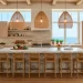 Bright coastal kitchen featuring bleached oak cabinets, woven rattan pendants, and travertine stone backsplash.