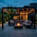 Wide view of a modern moody charcoal gray backyard patio at dusk with a fire pit and string lights.