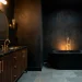 Luxurious moody bathroom featuring high-contrast brass hardware against dark matte black walls.