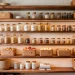 Beautifully organized boho-chic small pantry featuring natural wood shelves, woven baskets, and glass storage jars.