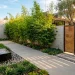Modern courtyard entryway with sleek concrete pavers, bamboo planters, and a teak slatted gate