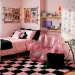 Y2K inspired bedroom decor featuring an inflatable pink chair, lava lamp, and checkerboard rug.