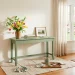 Freshly painted sage green wooden console table in a sunlit spring living room with paintbrushes and drop cloth.