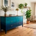 Wide panoramic view of a vintage dresser painted in a teal and navy ombre finish in a bright modern living room.