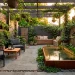 Compact modern urban patio featuring lush vertical gardens and a small ground-level pond reflecting warm sunlight