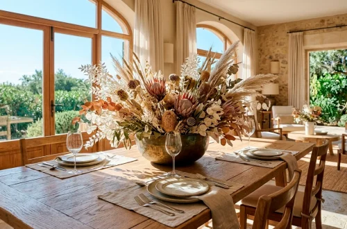 Large dried floral summer centerpiece on a wooden dining table in a sunlit room.