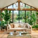 Wide view of a modern sunroom featuring black metal window frames, a brass chandelier, a glass coffee table, and lush greenery.