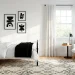 Wide view of a modern monochrome kids bedroom with black metal bed and geometric rug