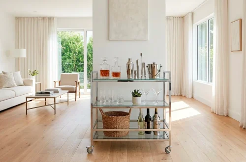 Bright living room featuring a sleek glass and chrome rolling bar cart near a sunny window.