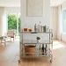 Bright living room featuring a sleek glass and chrome rolling bar cart near a sunny window.