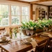 A beautiful rustic wood trough centerpiece filled with fresh spring tulips on a large oak farmhouse table.