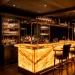 Luxurious home bar featuring a glowing onyx countertop in a dimly lit room