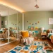 Wide view of a kid's bedroom featuring a sleek mirror-fronted wardrobe reflecting natural light and cozy decor.