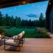 Minimalist Scandi-inspired back porch with light oak decking, modern black furniture, and cozy ambient evening lighting.