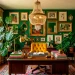 A colorful maximalist home office featuring jewel-toned walls, an eclectic gallery wall, and a yellow velvet chair.