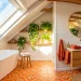 Sunlit attic bathroom featuring crisp white sloped ceilings, vibrant orange accents, and a freestanding soaking tub.