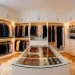 Luxurious walk-in closet featuring velvet hangers, a glass jewelry island, and warm LED lighting