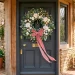 Large lush Easter wreath with dusty rose velvet ribbon on a dark charcoal front door with spring sunlight