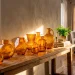 A cozy winter living room console table featuring beautiful amber glass vases catching warm golden sunlight.