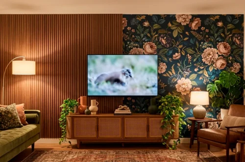 Eclectic living room TV wall featuring mixed textures of fluted wood and dark floral wallpaper.