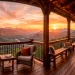 Wide horizontal view of a rustic balcony with wood and metal railings overlooking a mountain sunset