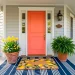 Beautifully styled spring porch featuring a layered navy striped rug and yellow lemon coir mat in front of a coral door