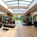 Modern home gym illuminated by bright natural light from large ceiling skylights over workout equipment