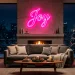Modern living room decorated for the holidays featuring a glowing pink neon sign and neon-lit Christmas tree