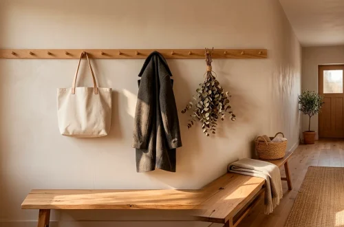 Beautifully styled narrow hallway featuring a long wooden peg rail with a wool coat and canvas bag.