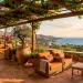 Sun-drenched Mediterranean porch featuring rustic terracotta floor tiles, oversized clay planters, and cozy rattan seating.