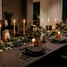 Luxurious modern dining table set with a dark charcoal linen tablecloth and flickering taper candles.