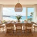 Spacious coastal dining room with natural jute rug under a wooden table and rattan chairs