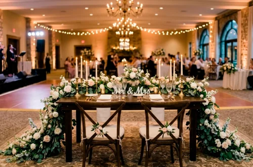 Elegant wedding sweetheart table with cascading floral runner and flickering taper candles
