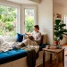 Wide view of a beautiful bay window reading nook featuring a custom tufted velvet cushion and cozy throw blankets.