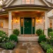 Moody emerald green front door with brass hardware on an elegant porch