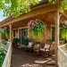 Lush spring wrap-around front porch featuring vibrant hanging baskets with petunias and sweet potato vines in the sun.