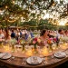Rustic wedding reception table decorated with glowing mason jars, wildflowers, and string lights.