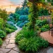 Wide view of a beautiful, deeply landscaped backyard utilizing optical illusions with a winding path and lighting.